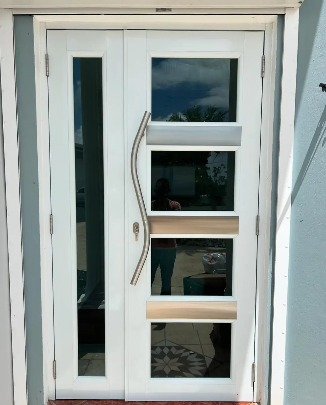 Puerta blanca con paneles de cristal y tirador curvo